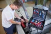 A man is working on a table saw with a toolbox open next to him. Produktbild-Vorschau