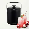 A black insulated ice bucket with a handle, placed next to two glasses of crushed ice drinks garnished with strawberries and mint. Berries are scattered around the glasses. Produktbild-Vorschau