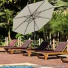 A patio umbrella shades several lounge chairs by a pool. Náhled obrázku produktu