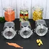 A collection of glass jars filled with food items and empty jars are arranged on a dark surface with a light wooden plank background. Náhled obrázku produktu