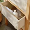 A close-up view of a bamboo storage unit with fabric drawers, containing towels and a dispenser bottle. Podgląd zdjęcia produktu