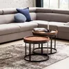 Zwei stapelbare Beistelltische Akola mit runder Sheesham-Holzplatte und schwarzem Metallgestell in Wohnzimmer-Szenerie. Produktbild-Vorschau