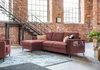 A modern living room with exposed brick walls and a large sectional sofa. Produktbild-Vorschau