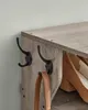 Close-up of a wooden shoe rack with black hooks and a brown purse strap hanging from one hook. Náhled obrázku produktu