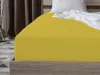 A close-up of a yellow fitted sheet on a bed.