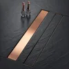 A close-up shot of a modern shower drain with a copper insert, set against a dark, textured surface. Produktbild-Vorschau
