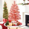 A pink Christmas tree is decorated with ornaments and placed on a table with gifts and a teddy bear. Another green Christmas tree is in the background. Anteprima dell’immagine prodotto