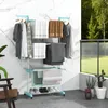 A multi-tiered drying rack with clothes and towels is shown in a modern bathroom or balcony setting. Náhľad obrázku produktu