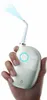 A hand holding a white and light green water flosser with a stream of blue water spraying from the nozzle. Náhled obrázku produktu