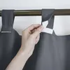 A hand is shown attaching a dark gray curtain to a curtain rod using a white loop and hook fastener. Produktbild-Vorschau