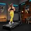 A woman is running on a treadmill in a home gym setting. Produktbild-Vorschau
