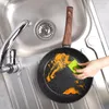 A hand is cleaning a frying pan in a kitchen sink. Náhled obrázku produktu