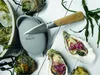 Oysters and an oyster knife are arranged on a white wooden surface, with some seaweed and ice visible. Voir les images du produit