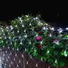 A string of white net lights is draped over a bush with pink roses and green leaves at night. Produktbild-Vorschau