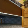 Close-up view of the underside of a wooden bed frame with LED strip lights illuminating the area below. Produktbild-Vorschau