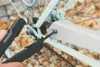 A person is using a Leatherman multitool to tighten a screw on a bicycle chain guard. Produktbild-Vorschau