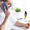 A man is on the phone while working at a desk. Produktbild-Vorschau
