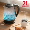 A glass electric kettle boiling water with blue LED illumination, next to a cup of coffee and a croissant on a wooden tray. Produktbild-Vorschau