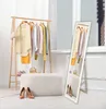 A room with a clothing rack, a mirror, and an ottoman, showcasing clothing and shoes. Náhled obrázku produktu