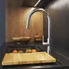 A kitchen sink area with a faucet, cutting board, and fruit. Produktbild-Vorschau