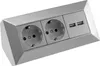 A silver-colored corner power strip with two standard European outlets and two USB ports, shown at an angle against a white background. Anteprima dell’immagine prodotto
