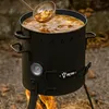 A black outdoor cooking pot filled with stew, being stirred by a ladle, sitting over a fire. Produktbild-Vorschau
