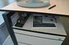 A close-up view of a desk with a power strip, a magazine, and a pen. Produktbild-Vorschau