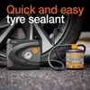 A tire sealant and an air compressor are shown next to a car tire on a paved surface. Produktbild-Vorschau