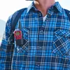 A person wearing a blue plaid shirt and a backpack, with a walkie-talkie clipped to the shirt pocket. Produktbild-Vorschau