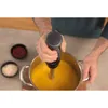 A person is using an immersion blender to blend soup in a pot. Anteprima dell’immagine prodotto