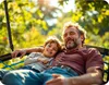 A father and son are relaxing on a swing in a garden. Podgląd zdjęcia produktu
