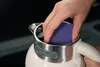 A hand is cleaning the inside of a kettle with a blue sponge. Podgląd zdjęcia produktu
