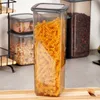 A clear shot of a transparent food storage container filled with fusilli pasta, placed on a wooden cutting board. Other storage containers are visible in the background. Podgląd zdjęcia produktu