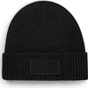 A black knitted beanie with a rectangular patch on the front. Anteprima dell’immagine prodotto
