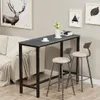 A bar table and two stools are set up in a room with a sofa and artwork on the wall. Podgląd zdjęcia produktu
