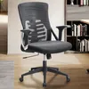 A black mesh office chair is shown in a room with wooden floors and a bookshelf in the background. Voir les images du produit