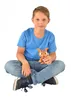 A young boy is sitting cross-legged on a white background, holding an orange toy figure. Voir les images du produit