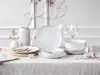 A table setting with white porcelain plates and bowls with gold trim, wine glasses, and decorative branches. Náhľad obrázku produktu