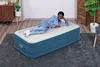 A woman is lying on an inflatable bed in a room. Produktbild-Vorschau