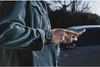 A person wearing a corduroy jacket and a watch is holding a smartphone. Produktbild-Vorschau
