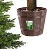 A Christmas tree stand with a tree trunk in it, next to a Christmas tree. The stand has a label with product information. Voir les images du produit
