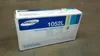 A Samsung toner cartridge box is placed on a concrete floor. Produktbild-Vorschau
