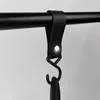 A black leather strap with a metal clasp is attached to a black rod, with a black hook hanging from it. Náhľad obrázku produktu