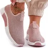 A person wearing pink slip-on sneakers.