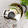 A top-down view of a pot with a glass lid, containing noodles and bay leaves, with scattered peppercorns on a grey surface. Náhled obrázku produktu