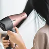 A person is using a rose gold and black hairdryer on their dark hair. Produktbild-Vorschau