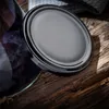 A close-up of a black jar lid on a rustic wooden surface, with plums visible in a jar to the left. Anteprima dell’immagine prodotto