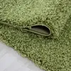 A close-up view of a green shaggy rug, showing its texture and the edge where it is folded. Podgląd zdjęcia produktu
