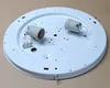 A white circular ceiling light fixture base with two light bulb sockets and a wiring connector block. Produktbild-Vorschau