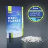 A bag of MRS Magnesium Bath Flakes is shown with some flakes spilled in front of it, against a dark gray background. A circular marketing graphic is to the right of the bag. Náhľad obrázku produktu
